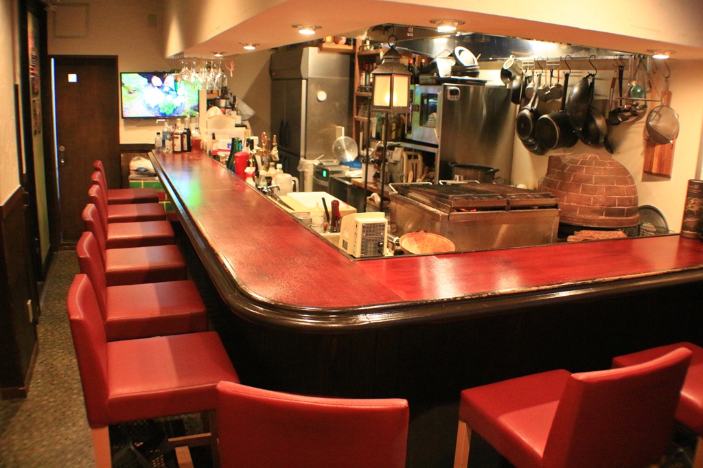 Grill＆Bar Linkの店内。赤い椅子が並ぶカウンターと、その内側の厨房